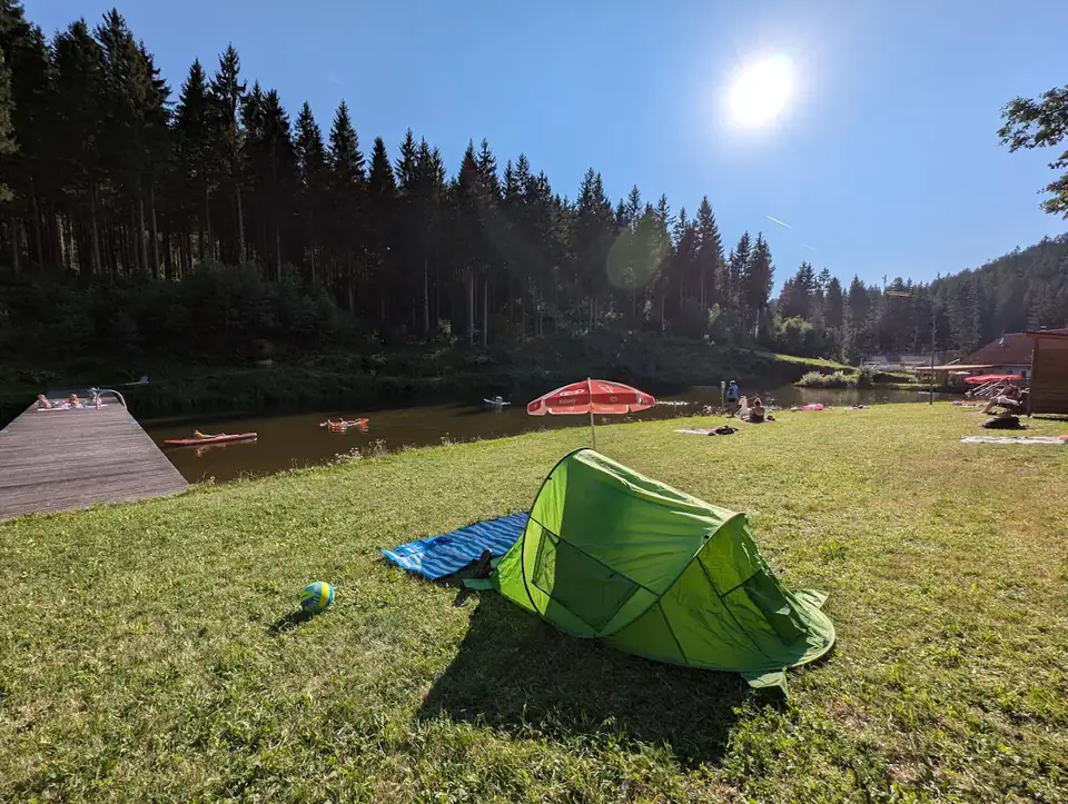 Liegewiese mit Zelt und Sonnenschirm am Waldbadteich